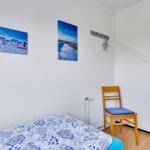 Schlafzimmer mit Bett, Stuhl und Wandbildern