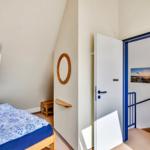 Schlafzimmer mit Bett, Fenster und Tür zu Treppenhaus.