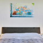 Schlafzimmer mit Bett, Nachttischen und Wandbild mit Fahrrad