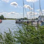 Hafen mit Segelbooten und blauem Haus am Wasser.