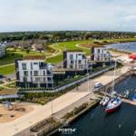 Hafen mit Booten, modernen Häusern und grünen Flächen am Wasser.