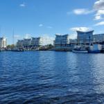 Hafen mit Booten und modernen Gebäuden am Wasser.
