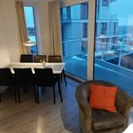 Essbereich mit Tisch und Stühlen, Sessel mit Kissen, Blick auf Terrasse und Hafen.