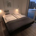 Schlafzimmer mit Doppelbett, großen Fenster und moderner Beleuchtung.