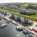 Aerial view of marina with boats and modern waterfront buildings.