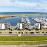 Modernes Haus am Hafen mit Booten und Grünflächen.