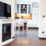 Wohnbereich mit Kamin und TV, Küche mit Esstisch und Küchenschränken.