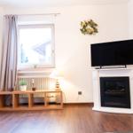 Wohnzimmer mit Fernseher, Kamin und Fenster mit Vorhang.