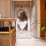 Dusche mit Bodenbelag aus Kieselsteinen und Wandbild einer Frau.