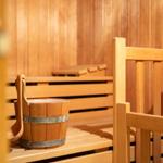 Sauna mit Holzbank und Eimer auf der Bank.