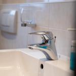 Waschbecken mit modernem Wasserhahn und blauem Seifenspender