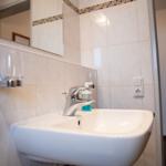 Waschbecken mit Spiegel und Flaschenhalter an der Wand.