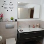 Bathroom with sink, mirror, and toilet. Wall decoration with stickers.
