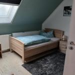 Bedroom with sloped ceiling, wooden bed, window, and nightstand.