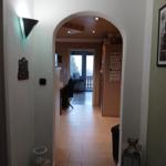 Hallway with arch leads to kitchen and dining area. Wall decor and floor tiles visible.