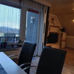 Dining area with view of landscape, living room with TV and wooden wall