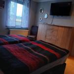 Two beds with striped bedcovers, wardrobe, and TV on the wall.