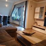 Living room with sofa, coffee table, and TV. Passage to kitchen with dining area.