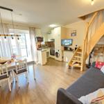 Living kitchen with dining area, sofa, and wooden staircase to upper level.