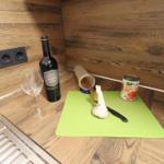 Kitchen area with wine bottle, spaghetti, garlic, and tomato can on green cutting board.