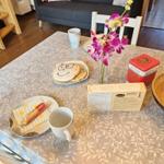 Table with tablecloth, mugs, flowers, and snacks