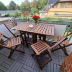 Terrace with wooden table and chairs, flowers, and view of garden and neighboring house.