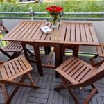 Wooden table with four chairs and flowers on balcony