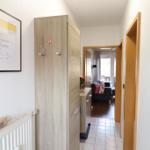 Hallway with wardrobe, radiator, and view into living area.