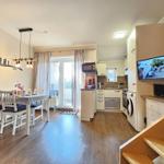 Living kitchen with dining table, TV, and balcony access.