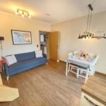 Living and dining area with sofa, table and chairs. Wooden floor and wall decoration.