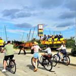 Horse-drawn carriages and cyclists near a harbor with information boards.
