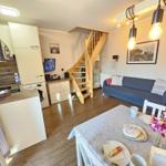 Living kitchen with dining area, sofa, and wooden staircase.