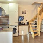 Kitchen with washing machine, TV, and wooden staircase to upper level.