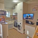 Kitchen with washing machine, TV, and wooden staircase