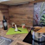 Kitchen with pot, spaghetti, garlic, and wine on wooden surface.