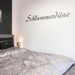 Schlafzimmer mit Bett, Wanddekoration und Beleuchtung.