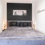 Schlafzimmer mit großem Bett, schwarzer Wand und Wandbild.