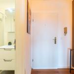 Eingangsbereich mit Tür, Spiegel und Badezimmer mit Dusche.