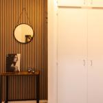 Eingangsbereich mit Holzwand, Spiegel und Kleiderschrank.