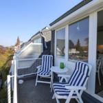 Terrasse mit zwei Stühlen und Tisch. Blick auf Garten und Nachbarhäuser.