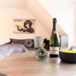 Runder Tisch mit Champagner, Gläsern und Trauben vor einem Sofa und Wandbild.