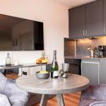 Küche und Essbereich mit runden Tisch, zwei Stühlen und Fernseher an der Wand.