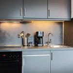 Küche mit Dunstabzug, Spüle, Kaffeemaschine und Backofen.