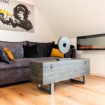 Ein Wohnzimmer mit grauem Sofa, Holzboden und moderner Wandheizung.