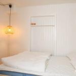 Schlafzimmer mit weißem Bett, Wandlampe und Fenster.