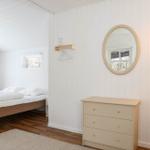 Schlafzimmer mit Bett, Schrank und Spiegel an weiß verputzten Wänden.
