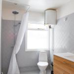 Badezimmer mit Dusche, Toilette und Waschbecken mit Spiegel.