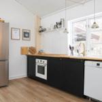 Küche mit Edelstahl-Kühlschrank, schwarzen Schränken und Holz Arbeitsplatte.