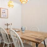 Esszimmer mit Holztisch, weißen Stühlen und Wandbild.