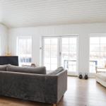 Wohnzimmer mit Sofa, Fenstern und Holzboden.
